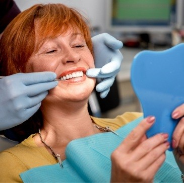 Dental patient admiring her new smile in mirror