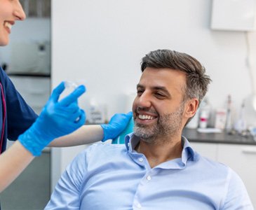 Man smiling with dentist holding clear aligner