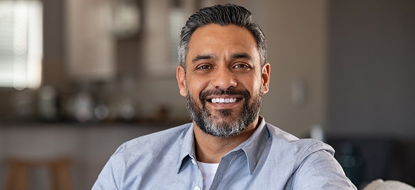 Man in blue shirt smiling on couch