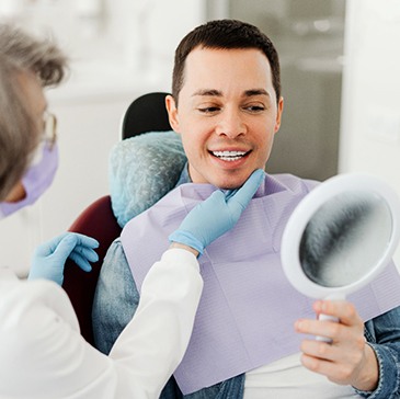 Man smiling at reflection in mirror with dentist