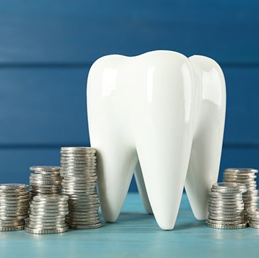 A large model tooth surrounded by stacks of silver coins