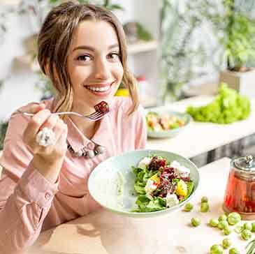 Woman smiling while eating salad at home